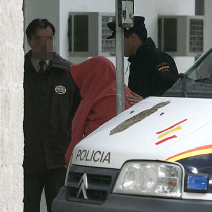 Dos agentes de policía trasladan ante el juez a uno de los detenidos en Marbella.