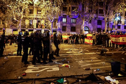 Agentes se agrupan al tiempo que manifestantes lanzan objetos contra ellos. 