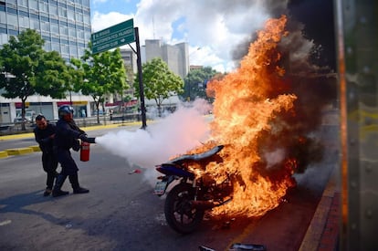 Dos miembros de la Guardia Nacional Bolivariana (GNB) tratan de apagar el fuego de una moto en llamas durante los enfrentamientos con los opositores.