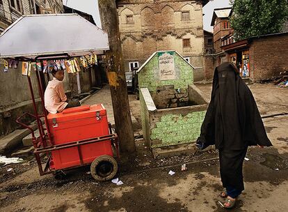 Mujer con burka en el barrio viejo de Srinagar y niño vendiendo. Se calculan unos 40.000 los huérfanos, tantos que se anula la capacidad de acogida habitual de las familias musulmanas.