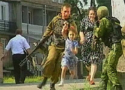 Imagen de televisión en la que un soldado ayuda a una niña a salir del colegio tomado por los terroristas.