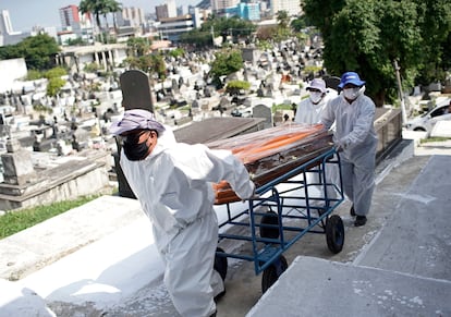 Trabajadores del cementerio de Nova Iguacu en Brasil cargan el ataud de un fallecido por coronavirus.