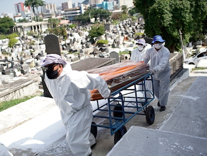 Trabajadores del cementerio de Nova Iguacu en Brasil cargan el ataud de un fallecido por coronavirus.