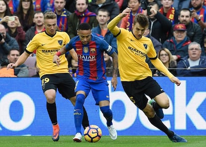 El davanter brasiler del Barcelona Neymar (centre) intenta avançar amb la pilota Javier Ontiveros (esquerra) i Diego Llorente (dreta), del Màlaga.