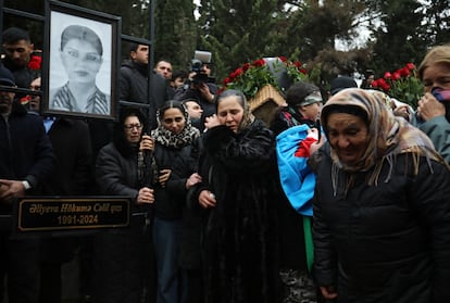 Un grupo de personas llora ante la tumba de la azafata Hokuma Aliyeva durante el funeral de los miembros de la tripulación del vuelo J2-8243 de Azerbaijan Airlines que se estrelló cerca de la ciudad kazaja de Aktau, en Bakú, Azerbaiyán, 29 de diciembre de 2024. 