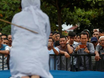 Una multitud de hombres se rien y graban con sus teléfonos móviles como una mujer recibe latigazos en público, acusada de mantener relaciones sexuales fuera del matrimonio en Banda Aceh (Indonesia).