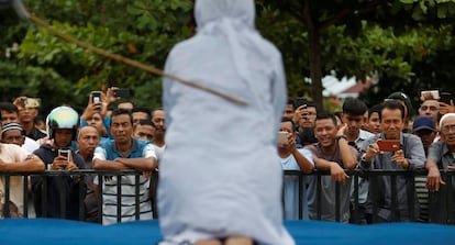 Una multitud de hombres se rien y graban con sus teléfonos móviles como una mujer recibe latigazos en público, acusada de mantener relaciones sexuales fuera del matrimonio en Banda Aceh (Indonesia).