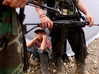 A boy sits among a group of FARC guerrillas in San Vicente del Caguán, in 2000.