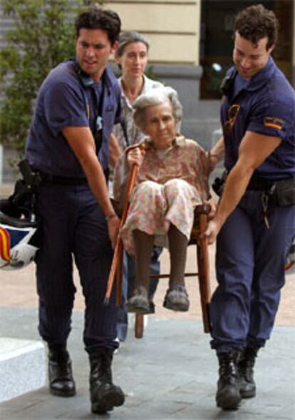 Una anciana es evacuada por dos bomberos en prevencin de que se extendiera el fuego. Varios edificios completos de la calle Almadn han sido desalojados.