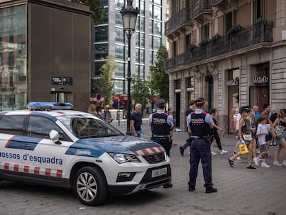 Dos agentes de seguridad ciudadana de los Mossos d'Esquadra vigilan en el Paseo de Gràcia en plena zona de afluencia turística.