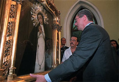 El alcalde, Alberto Ruiz-Gallardón, contempla el cuadro con la imagen de la Virgen de la Paloma, tras ser bajado del altar por los bomberos.