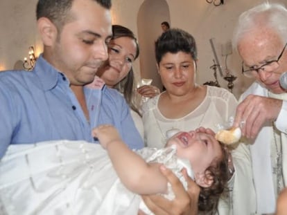 Natalia durante el bautizo con su padrino, las dos madres y el obispo Ra&uacute;l Vera.