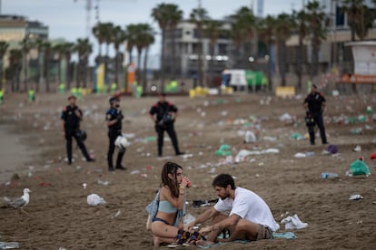 Una pareja espera a que los Mossos les desalojen de la playa.
