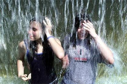 Dos de las participantes en la Cursa de El Corte Inglés se refrescan en la fuente de la plaza de Catalunya.