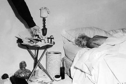 Imagen inédita del cadáver de Marilyn Monroe en el dormitorio de su casa. Un policía, probablemente el sargento Jack Clemmons, señala las pastillas que provocaron la muerte de la actriz.