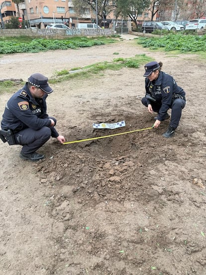 Dos policías locales miden el socavón provocado por un artefacto pirotécnico en un solar de València la pasada madrugada.