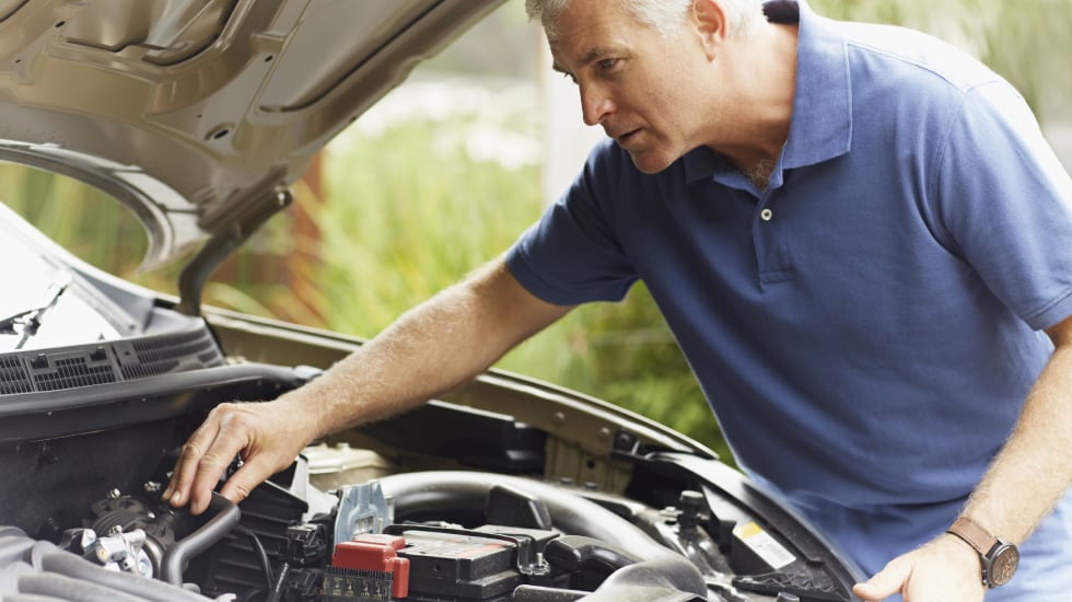 Un hombre supervisa el motor de su coche.