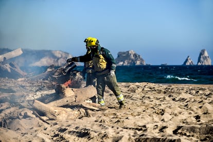 Dos técnicos del Grupo Especial de Prevención de Incendios Forestales queman troncos acumulados por el temporal en la desembocadura del río Ter.