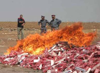 Dos gendarmes observan cómo arde un alijo de tabaco.