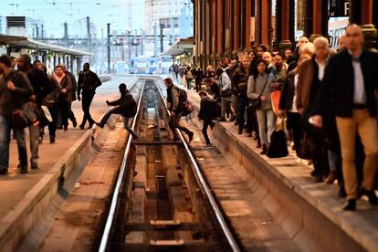 Passageiros cruzam as vias do trem em uma estação em Paris (França).