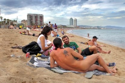 Un joven tomando el sol desnudo en la playa de Sant Sebastià.