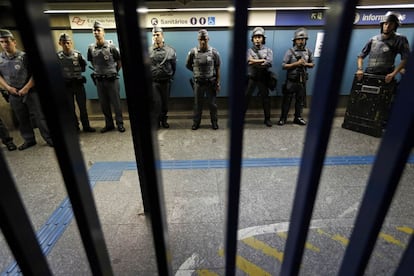 Policiais se mantêm atrás dos portões fechados em uma das entradas da estação Ana Rosa do metrô de São Paulo.