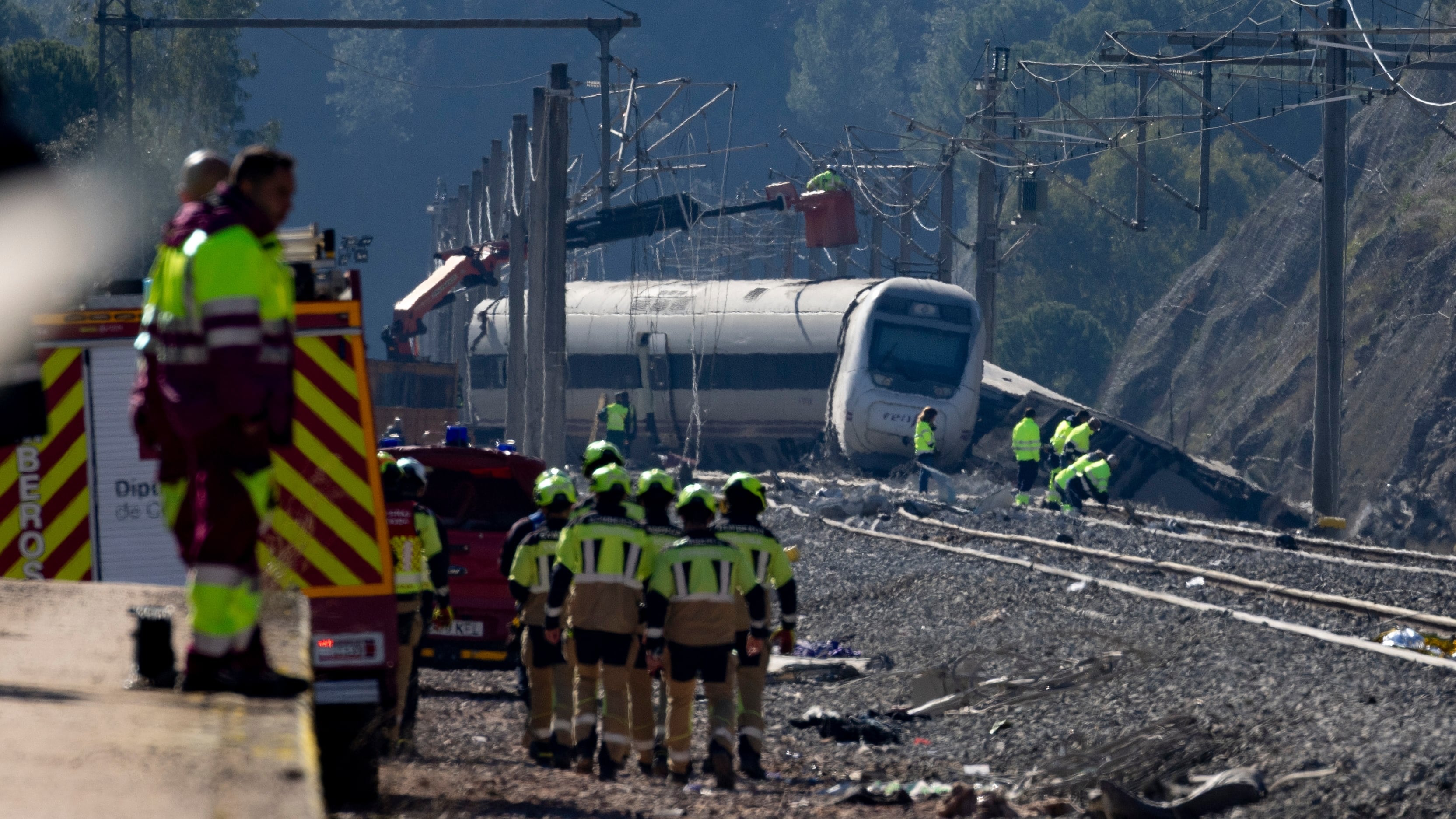 Un operario en una grúa trabaja en las catenarias por encima del tren Alvia accidentado.