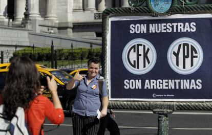Una mujer posa junto a un cartel de apoyo a la expropiación de la petrolera YPF.