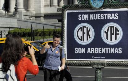 Una mujer posa junto a un cartel de apoyo a la expropiaci&oacute;n de la petrolera YPF.