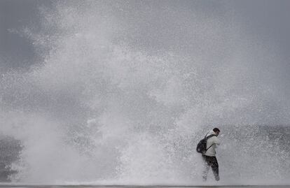 Un ciudadano desafía el fuerte oleaje en la playa de Barceloneta, este domingo en Barcelona.
