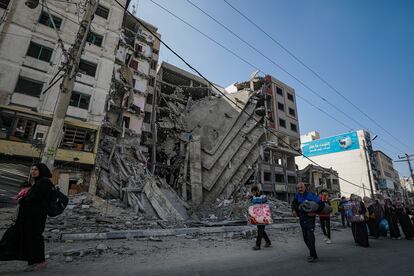 Varios residentes pasan junto a un edificio parcialmente destruido mientras evacuan la ciudad de Gaza, este miércoles. 
