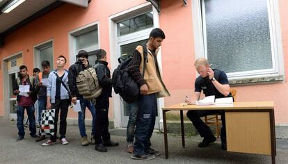 Un policía alemán registra a un grupo de refugiados.