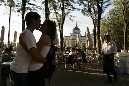 Jovens beijam-se em Madri com a Catedral de Almudena ao fundo.