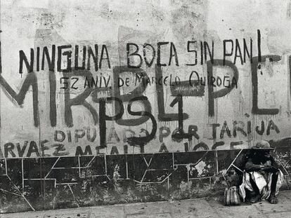 Una mujer sentada delante de una pared con pintadas, en una calle de Tarija, Bolivia.