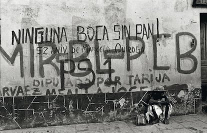 Una mujer sentada delante de una pared con pintadas, en una calle de Tarija, Bolivia.