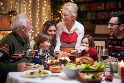 Happy mature woman serving dessert to her family after Christmas dinner.