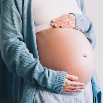 Beautiful pregnant woman holds hands on her belly. Happy mother waiting for baby birth. Pregnancy, maternity, preparation and expectation concept.