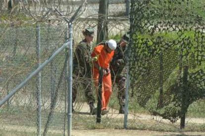 Dos soldados de EE UU escoltan a un preso islamista en el campo de detención de la base de Guantánamo.