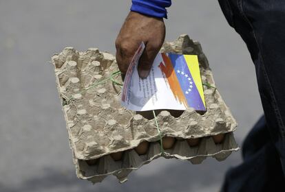 Un hombre venezolano porta un paquete de huevos junto a un papel  entregado por los políticos venezolanos en el exilio, invitando a la gente a salir a las calles el 23 de febrero para apoyar una entrega de ayuda planeada a Venezuela, en La Parada (Colombia).