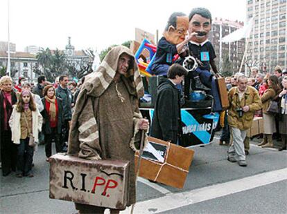 Manifestantes en A Coruña portan maletas alusivas a la emigración y muñecos de Manuel Fraga y José María Aznar ayer.