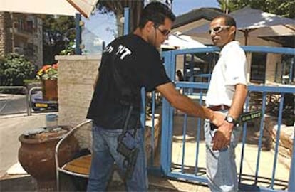 Un guardia de seguridad revisa con un detector de metales a un cliente antes de entrar en el café Moment.