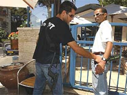 Un guardia de seguridad revisa con un detector de metales a un cliente antes de entrar en el café Moment.