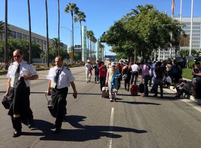 Un grupo de pasajeros y personal del aeropuerto caminan por Century Boulevard, en las inmediaciones del aeropuerto del Los &Aacute;ngeles. 