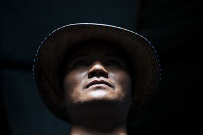 Kyaw Zay Ya con el sombrero tradicional de los trabajadores birmanos. Actualmente está en paro. Para pagar los gastos diarios alquila su habitación, de unos 20 metros cuadrados, a otros dos hombres. En una encuesta reciente realizada en Tailandia por la Organización Internacional para las Migraciones (OIM), el 57% de los entrevistados declaró que el principal problema al que se enfrentan los no tailandeses desde el estallido de la covid-19 es la insuficiencia de sus ingresos. Aunque en mayo de 2020 el Gobierno tailandés puso en marcha una serie de medidas de estímulo para ayudar a las empresas y a las personas en apuros, a menudo los emigrantes no pueden acceder a los subsidios debido a los obstáculos legales o al miedo a la deportación. Kyaw Zay Ya tiene dos hijos de 17 y 10 años que viven en Myanmar con sus abuelos. "Cuando se cierre el caso me gustaría volver a mi país", afirma.