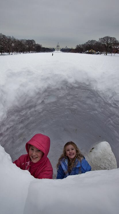 Dos niñas juegan con la nieve en el Nacional Mall, con el Capitolio al fondo.