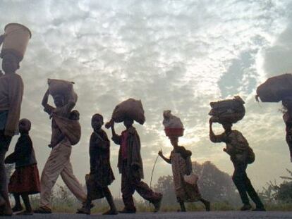 Refugiados ruandeses caminan con sus pertenencias.