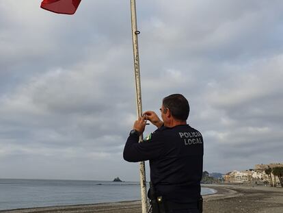 Un policía iza la bandera roja en la playa de Almuñécar (Grandada)