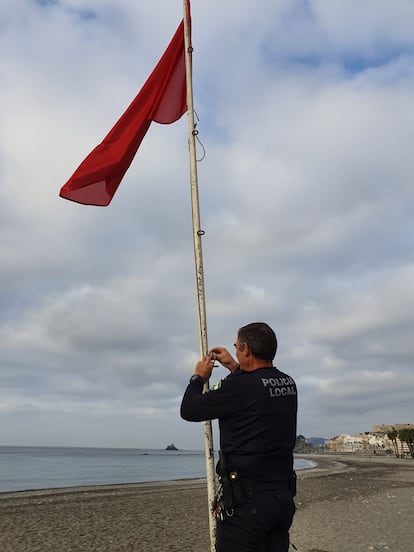 Un policía iza la bandera roja en la playa de Almuñécar (Grandada)