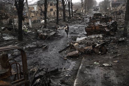 Una mujer camina entre vehículos blindados rusos destruidos en Bucha, ciudad en las afueras de Kiev. Desde la retirada de los soldados de Putin el jueves y hasta este lunes, se ha dado sepultura a 340 civiles en una fosa común, según fuentes municipales.