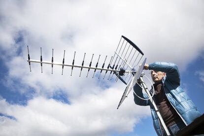 Un antenista cambia una antena antigua y resintoniza una nueva con amplificador de señal en una casa.